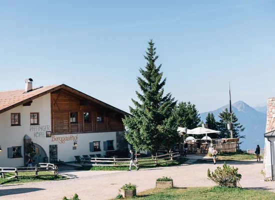 Rifugio Piffinger Köpfl con terrazza e panorama montuoso in soleggiata giornata estiva.